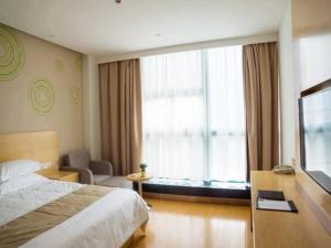 une chambre d'hôtel avec un lit et une grande fenêtre dans l'établissement GreenTree Inn Nantong Qidong Binhai Industrial Park Nanhai RoadExpress Hotel, à Qidong