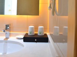 La salle de bains est pourvue d'un lavabo et de 3 tasses sur un comptoir. dans l'établissement GreenTree Inn Suzhou Yongqiao District Nanxiang Hengtai City Business Hotel, à Suzhou