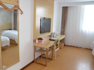 a room with a desk with a television and a bed at GreenTree Inn Tangshan Lubei District Hancheng Likang Hospital Express Hotel in Tangshan