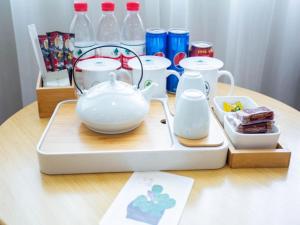 a tea set on a wooden table with milk bottles at GreenTree Inn ShangHai SongJiang SongDong Business Hotel in Songjiang