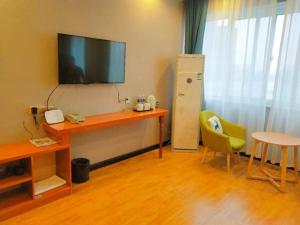 Zimmer mit einem Schreibtisch, einem TV und einem Stuhl in der Unterkunft Shell Kaifeng City Lancao County Women and Children Hospital Hotel in Kaifeng