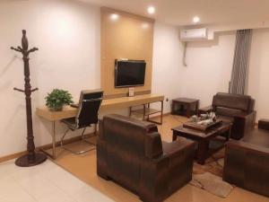 a living room with couches and a desk with a television at GreenTree Inn Wulanchabu High Speed Railway Station Huaiyuan South Road Express Hotel in Pingdiquan