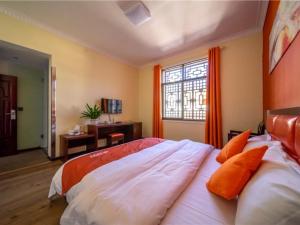 大理市にあるShell Dali City Dali Ancient Town South Gate Hotelのベッドルーム1室(オレンジ色のカーテンが付いた大型ベッド1台付)