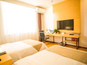 a hotel room with two beds and a desk with a television at GreenTree Inn Jinzhong Yuci Old Town Express Hotel in Jinzhong
