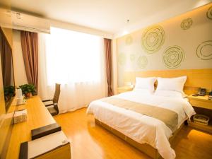 a bedroom with a large bed and a television at GreenTree Inn Jinzhong Yuci Old Town Express Hotel in Jinzhong