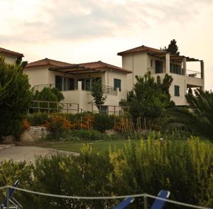 ein großes weißes Haus inmitten eines Gartens in der Unterkunft Il Villaggio in Chrani