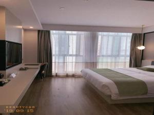 Habitación de hotel con cama grande y escritorio. en Gya Jiaxing Pinghu City Wuyue Square Shengli Road Hotel, en Jiaxing