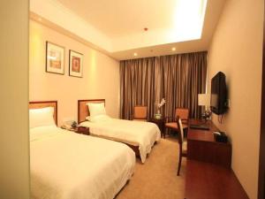 ein Hotelzimmer mit 2 Betten, einem Schreibtisch und einem TV in der Unterkunft GreenTree Inn ShanDong YanTai FuShan District YongDa Street Express Hotel in Yantai