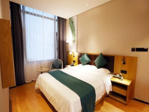 a hotel room with a large bed and a window at GreenTree Inn Zhengzhou Airport in Zhengzhou