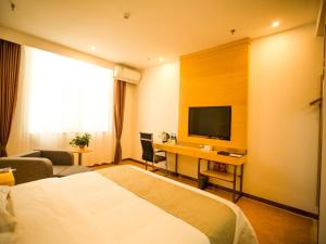 a hotel room with a bed and a desk with a television at GreenTree Inn Jinzhong Yuci Old Town Express Hotel in Jinzhong