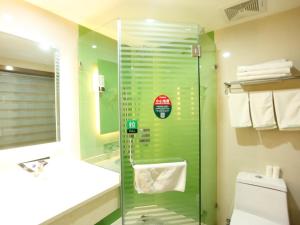 a bathroom with a glass shower with a toilet and a sink at GreenTree Inn Zhangye Liangjiadun Town Zhangnin Road Hotel in Zhangye