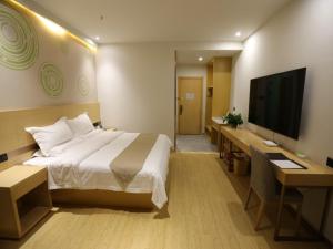 a hotel room with a bed and a flat screen tv at GreenTree Inn Dezhou Bus Station Train Station Express Hotel in Dezhou
