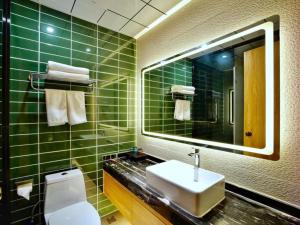 ein grün gefliestes Bad mit einem Waschbecken und einem Spiegel in der Unterkunft GreenTree Inn Changzhou Xuebu Eastern Salt Lake City in Changzhou