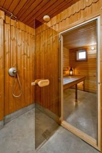 een badkamer met een douche en een houten muur bij Saulės Slėnis in Plateliai