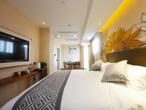a bedroom with a large bed with a tv on the wall at GME Hefei Sanxiaokou Chenghuang Temple Xinghua Park Hotel in Hefei