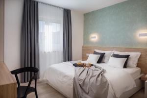 a bedroom with a white bed with a chair and a window at Villa VinSun in Vinišće
