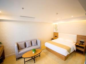a bedroom with a bed and a couch and a table at GreenTree Inn Liao Cheng Shen Country Bus Station Business Hotel in Liaocheng
