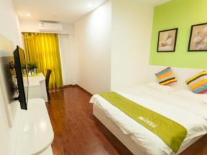 a bedroom with a white bed and a green wall at Shell Hefei Economic Development Zone Hong Kong and Macao Square Hotel in Hefei