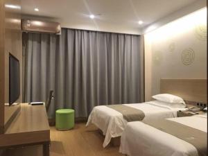a hotel room with two beds and a television at GreenTree Inn Jinzhong Xiyang County Bus Station Business Hotel in Xiyang