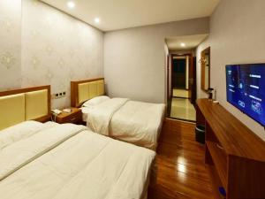 a hotel room with two beds and a flat screen tv at Shell Zhaozhong Ancient Street, Jinzhong County Railway Station Hotel in Qixian