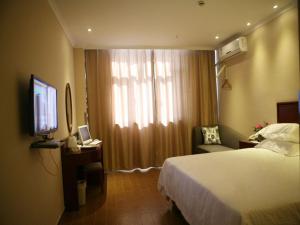 a hotel room with a bed and a television at GreenTree Inn Xinjiang Tulufan North Xihuan Road Express Hotel in Turfan