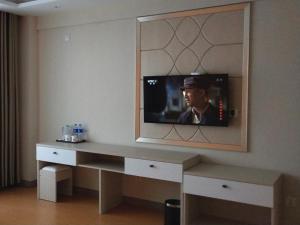 a room with a desk with a tv on the wall at Shell Chengde Xinglong County Banbishan Town Hotel in Xiabancheng