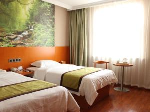a hotel room with two beds and a painting on the wall at Shell Rizhao Donggang District Bus station Hotel in Rizhao