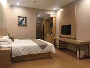 Schlafzimmer mit einem Bett, einem Schreibtisch und einem TV in der Unterkunft GreenTree Inn Jinzhong Xiyang County Bus Station Business Hotel in Xiyang
