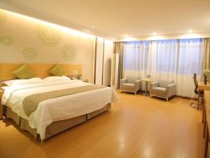 a hotel room with a large bed and two chairs at GreenTree Inn Huaibei Suixi county Sandikou Business Hotel in Huaibei