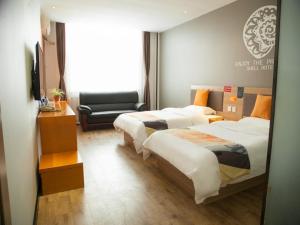 a hotel room with two beds and a chair at Shell Tangshan Caofeidian District Xinghai Mingdu Plaza Hotel in Tangshan