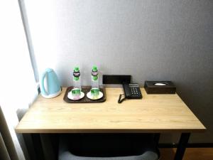 a wooden desk with a telephone and two bottles on it at GreenTree Inn Lanzhou Donghu Square Provincial People's Hospital in Lanzhou