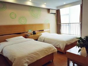 ein Hotelzimmer mit 2 Betten und einem Fenster in der Unterkunft GreenTree Inn qinghai xining jianguo road railway station express hotel in Xining