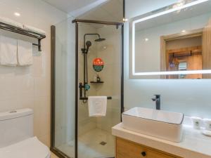 a bathroom with a shower and a sink and a mirror at GreenTree Inn Hefei Sanlian College Anda Qingyuan Campus Subway Station in Wangdaying
