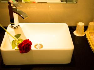 a white sink with a red rose on it at Shell Tangshan Caofeidian District Xinghai Mingdu Plaza Hotel in Tangshan