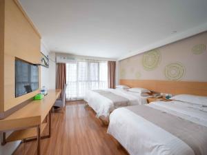 a hotel room with two beds and a flat screen tv at GreenTree Inn Yancheng National Fitness Center Express Hotel in Yancheng