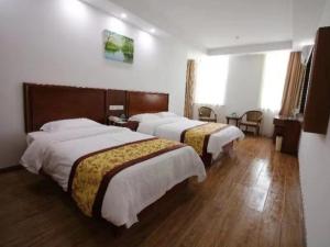 two beds in a hotel room with wooden floors at GreenTree Inn Jiangsu Changshu City Longying Square Express Hotel in Changshu