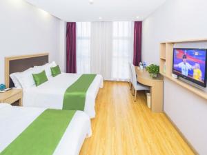 a hotel room with two beds and a flat screen tv at GreenTree Inn Tianjin Xiqing Development Zone Renrenle Square Express Hotel in Tianjin