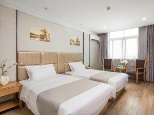 a hotel room with two beds and a table at GreenTree Inn Jiangsu Yancheng Yandu Bus Station Middle Daqing Road Express Hotel in Yancheng