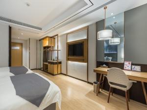 ein Hotelzimmer mit einem Bett, einem Schreibtisch und einem TV in der Unterkunft GYA Xuzhou High Speed Railway Station West Exit Station Hotel in Xuzhou