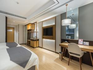 a hotel room with a bed and a desk and a television at GYA Xuzhou High Speed Railway Station West Exit Station Hotel in Xuzhou