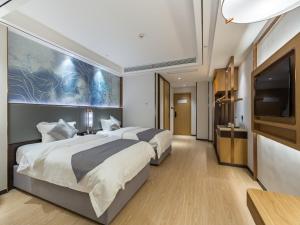 a hotel room with two beds and a flat screen tv at GYA Xuzhou High Speed Railway Station West Exit Station Hotel in Xuzhou