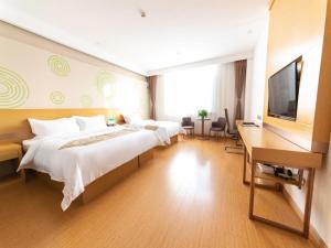 a bedroom with two beds and a desk and a television at GreenTree Inn Baoding City Cangzhou Guanyun West Road Business Hotel in Zhuozhou