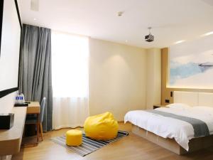 a bedroom with a bed and a yellow ottoman at VX hotel Nanjing South Railway Station Daming Road Metro Station in Nanjing