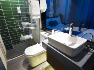 a bathroom with a sink and a toilet and a mirror at GreenTree Rizhao Lanshan Coach Station Hotel in Rizhao