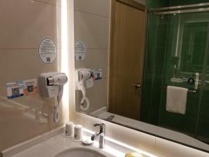 a bathroom with a sink and a shower and a mirror at GreenTree Heze Changcheng Road Tianhua E-commerce Logistics Park Express Hotel in Heze