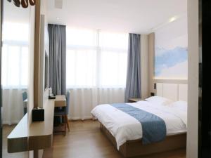 um quarto com uma cama, uma secretária e janelas em VX hotel Nanjing South Railway Station Daming Road Metro Station em Nanquim