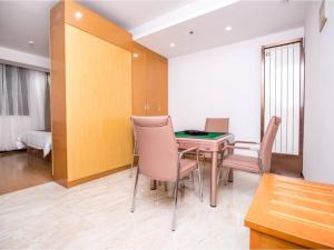 um quarto com uma mesa e cadeiras e um quarto em GreenTree Inn Xuchang Yucheng County Ziyun Avenue Business Hotel em Xuchang
