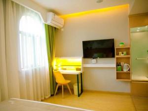 a bedroom with a desk and a television and a window at Vatica Fuyang Linquan County Jiangziya Square Hotel in Fuyang