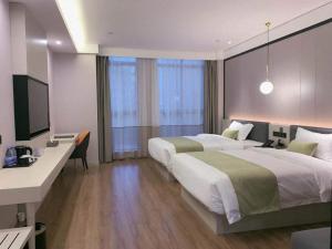 a hotel room with two beds and a desk and a television at Gya Jiaxing Pinghu City Wuyue Square Shengli Road Hotel in Jiaxing