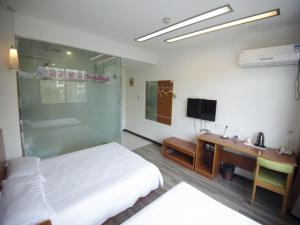 1 dormitorio con 1 cama, escritorio y TV en Shell Binzhou Bincheng District Yellow River Four Road Hotel, en Binzhou